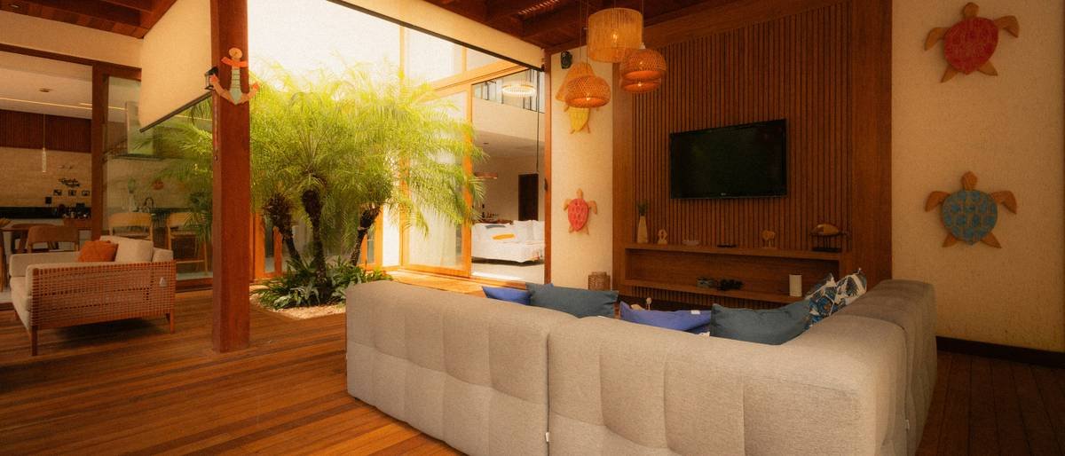 Authentic coastal cottage living room featuring slipcovered sofa, rattan armchair, weathered oak coffee table, and linen curtains with natural light