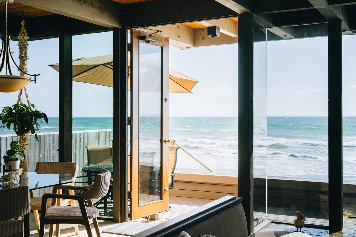 Infographic showing core materials in coastal beach home decor: rattan, whitewashed wood, linen, jute, and weathered teak with moisture resistance ratings and sourcing notes