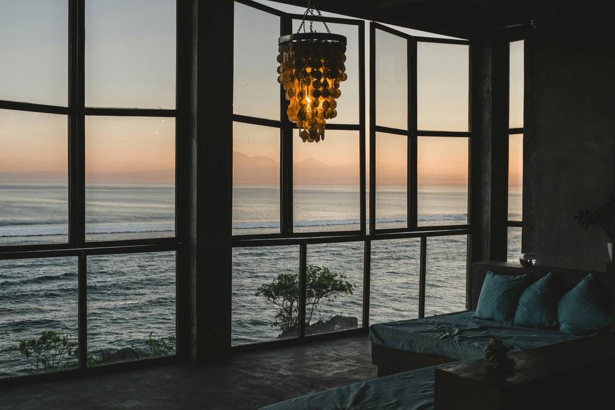 Bedroom showcasing interior design coastal style with sheer curtains, light oak bed frame, and sea-inspired neutral bedding