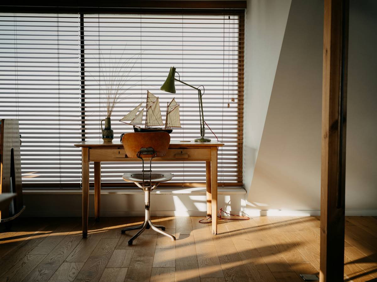 Minimal coastal style office furniture setup with teak desk and linen chair by window